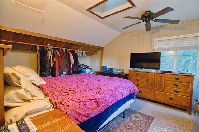 carpeted bedroom featuring vaulted ceiling, ceiling fan, and wooden walls