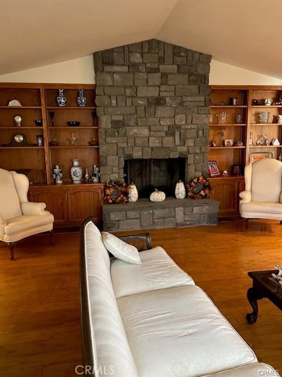 living room with a stone fireplace, dark wood-type flooring, and vaulted ceiling