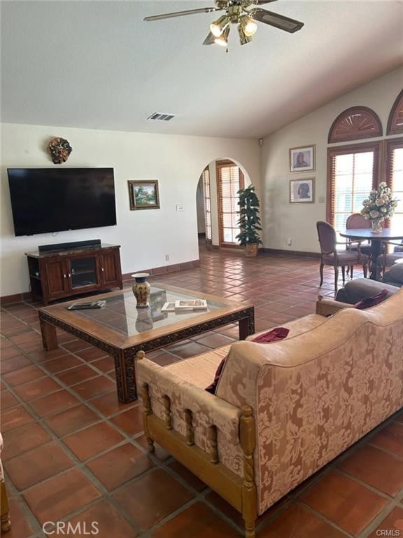 tiled living room with ceiling fan, a healthy amount of sunlight, and vaulted ceiling