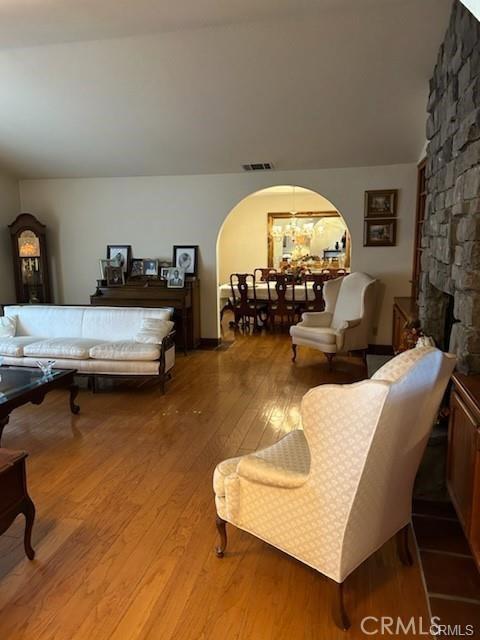 bedroom featuring a fireplace, light wood-type flooring, a chandelier, and vaulted ceiling