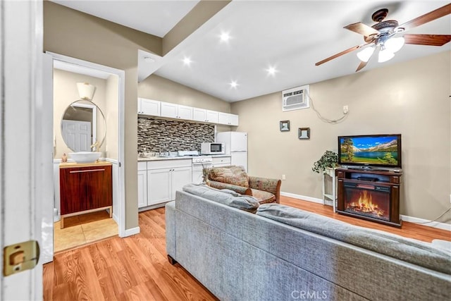 living room with ceiling fan, a wall mounted AC, and light hardwood / wood-style floors