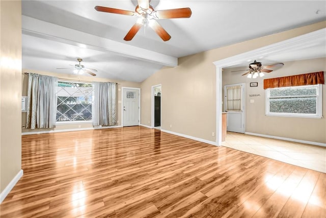 unfurnished living room featuring vaulted ceiling with beams, a healthy amount of sunlight, and light wood-type flooring