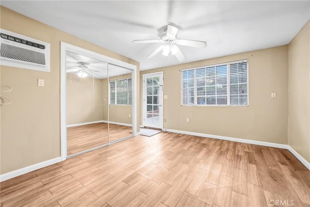 interior space featuring ceiling fan, an AC wall unit, plenty of natural light, and light wood-type flooring