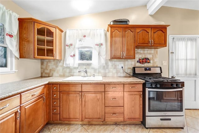 kitchen with sink, vaulted ceiling with beams, tasteful backsplash, stainless steel gas range oven, and light tile patterned floors