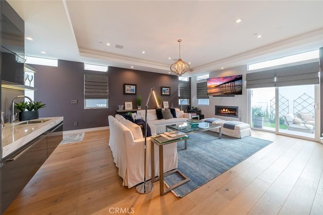 living room with light hardwood / wood-style floors, an inviting chandelier, and sink