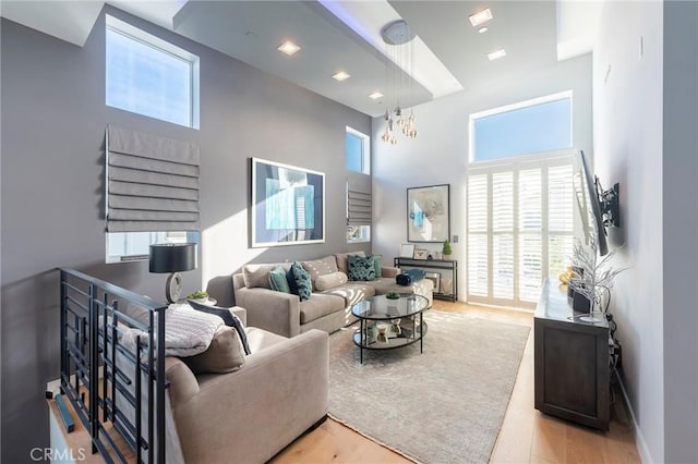 living room featuring a healthy amount of sunlight, a high ceiling, and light hardwood / wood-style flooring