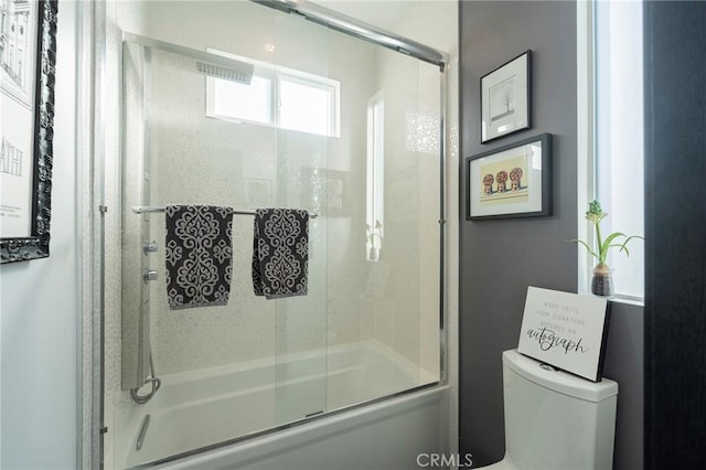 bathroom featuring toilet and combined bath / shower with glass door