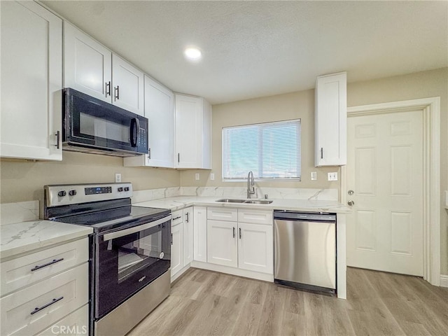 kitchen featuring white cabinets, stainless steel appliances, light hardwood / wood-style flooring, and sink