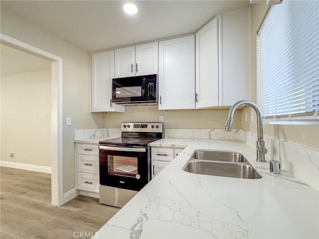 kitchen featuring stainless steel range with electric stovetop, sink, light stone countertops, light wood-type flooring, and white cabinetry