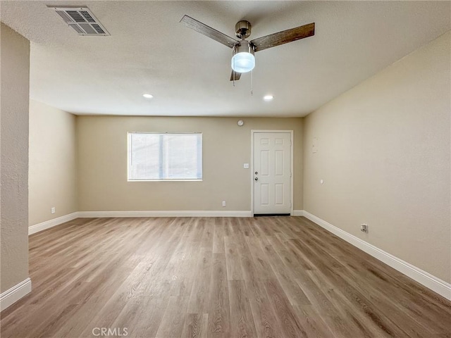 empty room with ceiling fan and light hardwood / wood-style floors