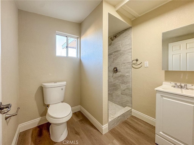 bathroom featuring toilet, hardwood / wood-style floors, vanity, and a tile shower