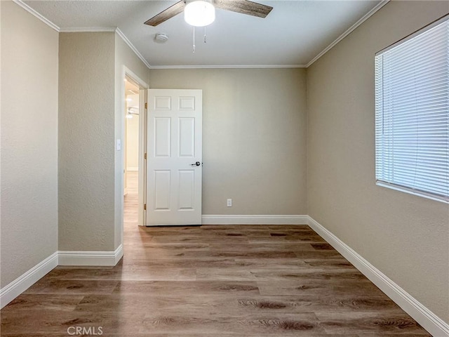 spare room featuring ceiling fan, hardwood / wood-style floors, a healthy amount of sunlight, and ornamental molding