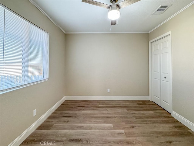 unfurnished bedroom featuring a closet, hardwood / wood-style flooring, ceiling fan, and ornamental molding