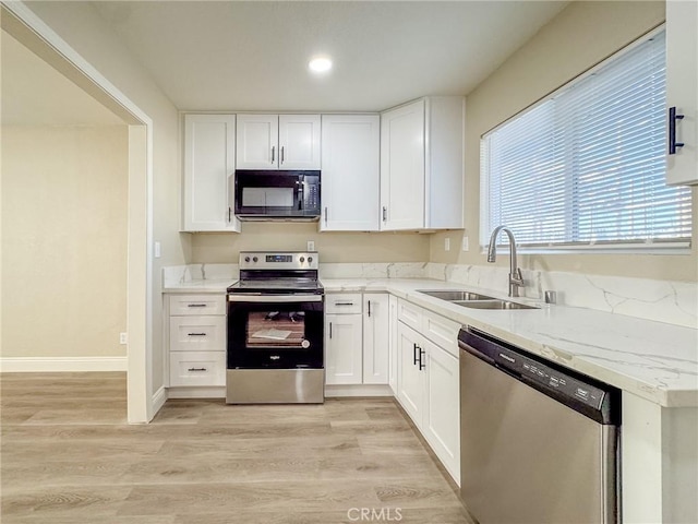 kitchen featuring white cabinetry, sink, light hardwood / wood-style floors, and appliances with stainless steel finishes