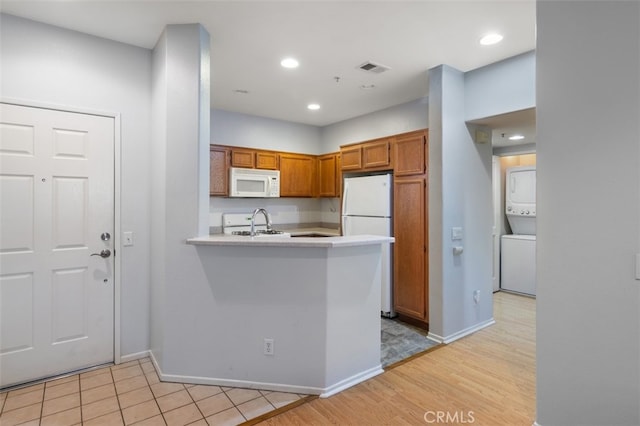 kitchen featuring kitchen peninsula, white appliances, sink, and light tile patterned floors