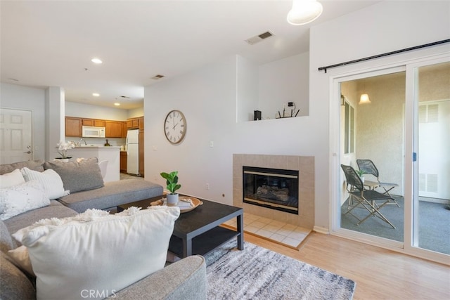 living room with light hardwood / wood-style floors and a tiled fireplace