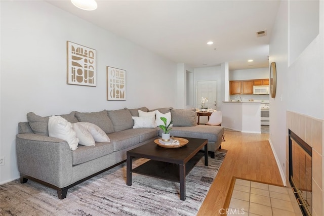 living room featuring a tile fireplace and light hardwood / wood-style floors