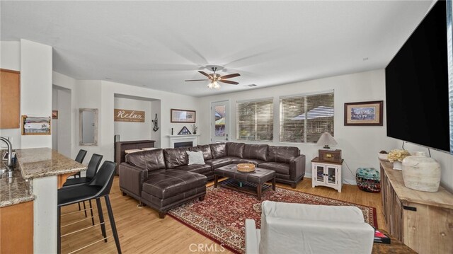 living room featuring light wood-type flooring, ceiling fan, and electric panel