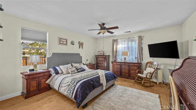 bedroom featuring ceiling fan, multiple windows, and light hardwood / wood-style flooring