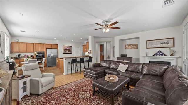 living room with ceiling fan and light hardwood / wood-style flooring