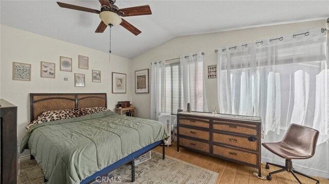 bedroom with ceiling fan, light hardwood / wood-style floors, and vaulted ceiling