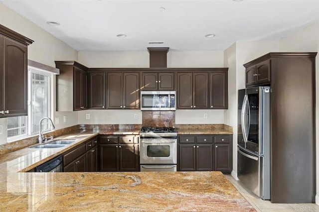 kitchen featuring light stone counters, dark brown cabinetry, stainless steel appliances, sink, and light tile patterned floors