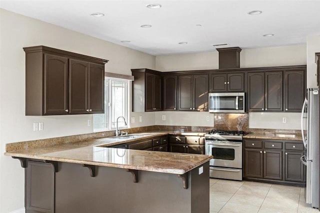 kitchen with kitchen peninsula, appliances with stainless steel finishes, a kitchen breakfast bar, and sink