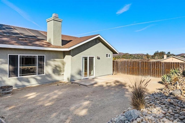 rear view of property featuring a patio and solar panels