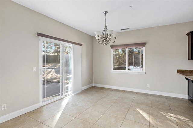 unfurnished dining area with light tile patterned floors, a healthy amount of sunlight, and a notable chandelier