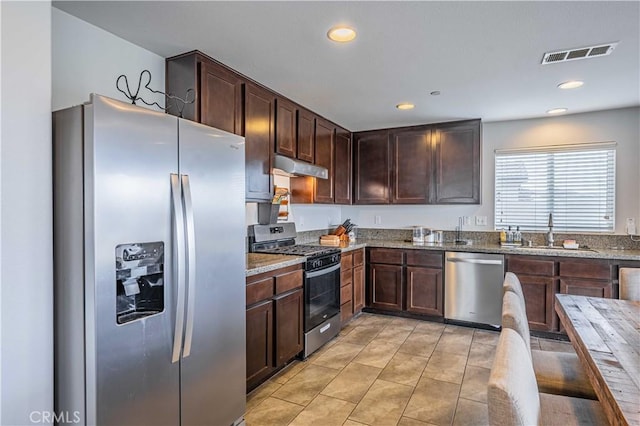 kitchen featuring stainless steel appliances, sink, light tile patterned floors, and dark brown cabinetry