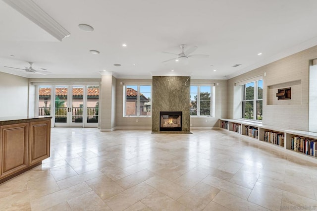 unfurnished living room with ceiling fan, a large fireplace, and ornamental molding