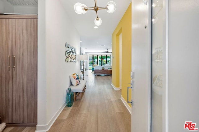 hallway with a notable chandelier and light wood-type flooring