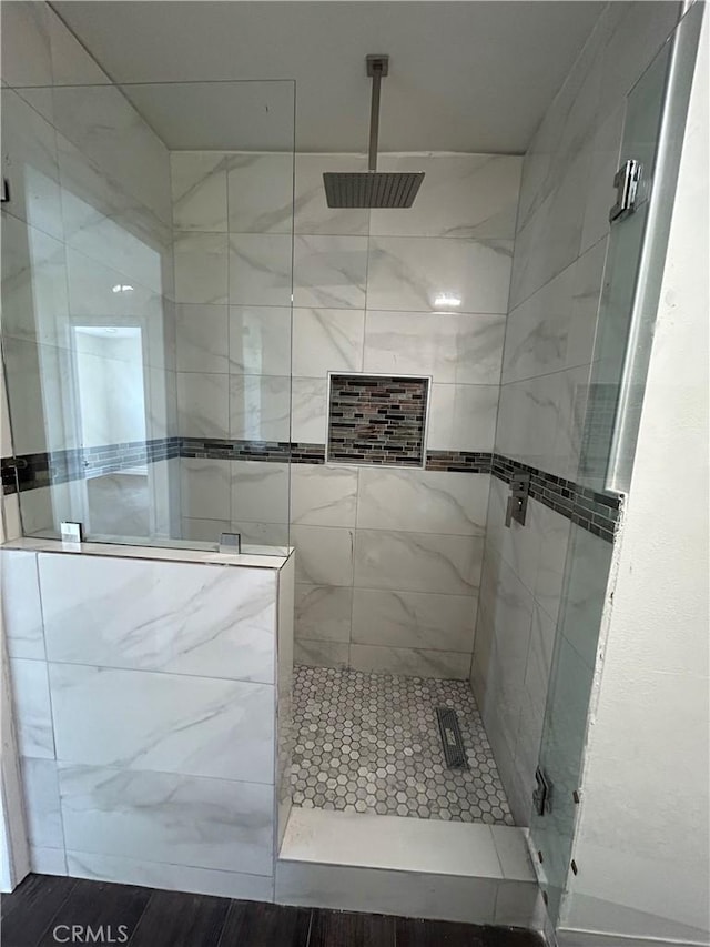 bathroom with tiled shower and wood-type flooring