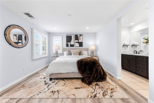 bedroom featuring sink, light hardwood / wood-style flooring, and ensuite bath