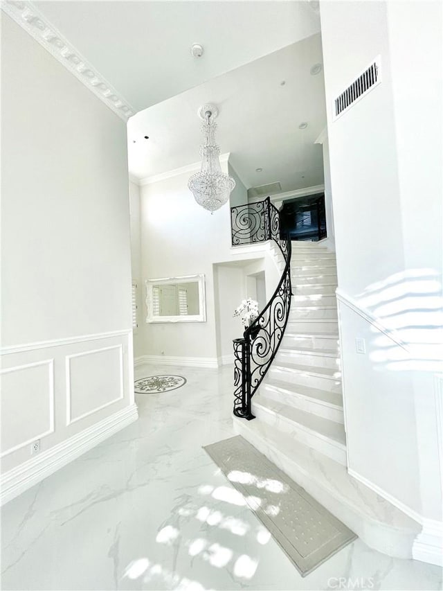 stairway with an inviting chandelier and ornamental molding