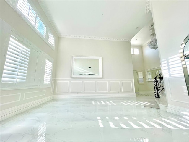 interior space featuring a healthy amount of sunlight, ornamental molding, and a high ceiling