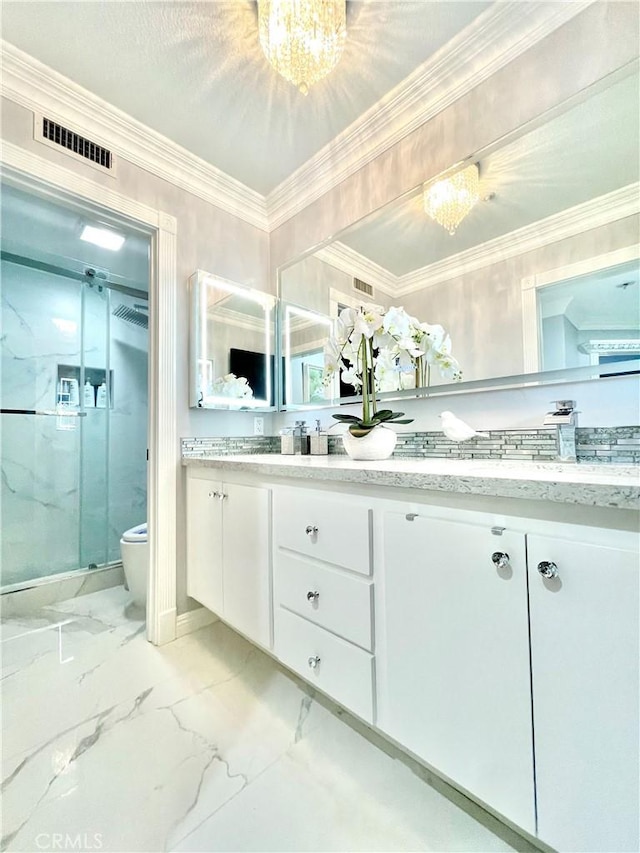 bathroom featuring vanity, toilet, ornamental molding, a shower with shower door, and a chandelier