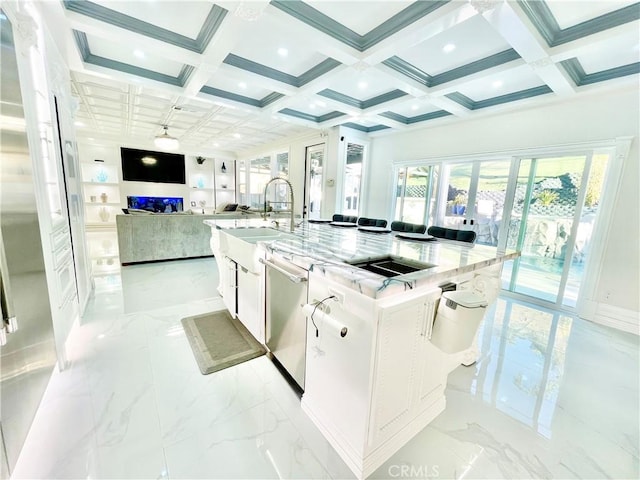 kitchen with sink, stainless steel dishwasher, a large island, light stone counters, and white cabinetry