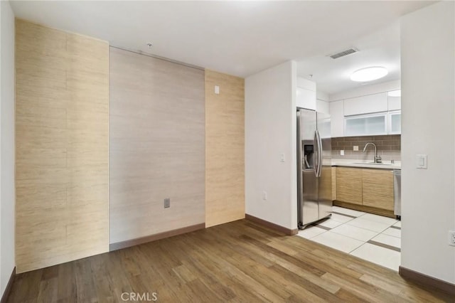 spare room featuring light wood-type flooring, tile walls, and sink