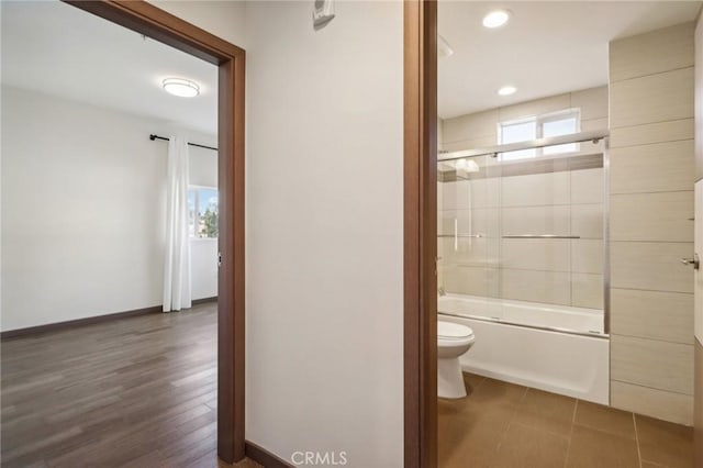 bathroom featuring shower / bath combination with glass door, wood-type flooring, and toilet