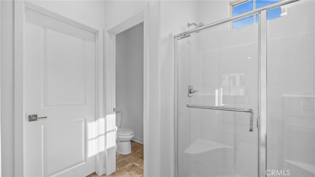 bathroom featuring toilet and an enclosed shower