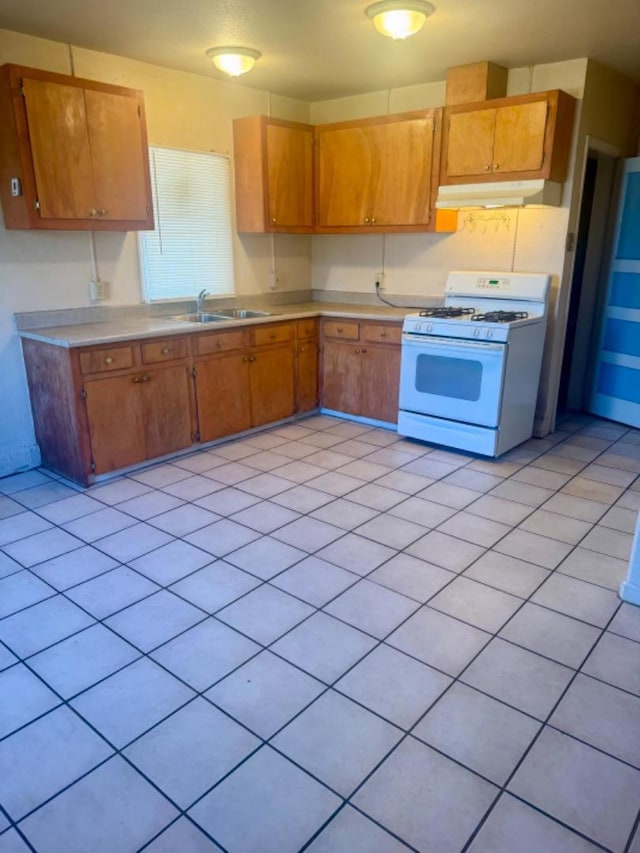 kitchen with white range with gas stovetop, light tile patterned floors, and sink