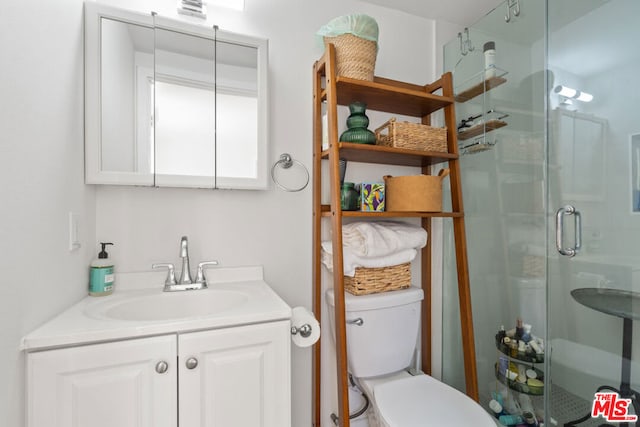 bathroom with vanity, toilet, and a shower with door