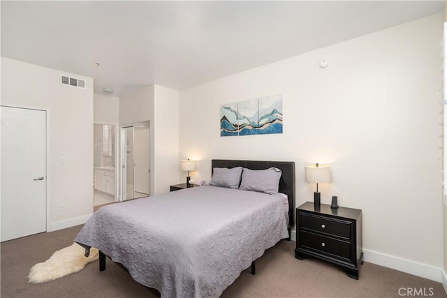 bedroom with ensuite bathroom and light colored carpet