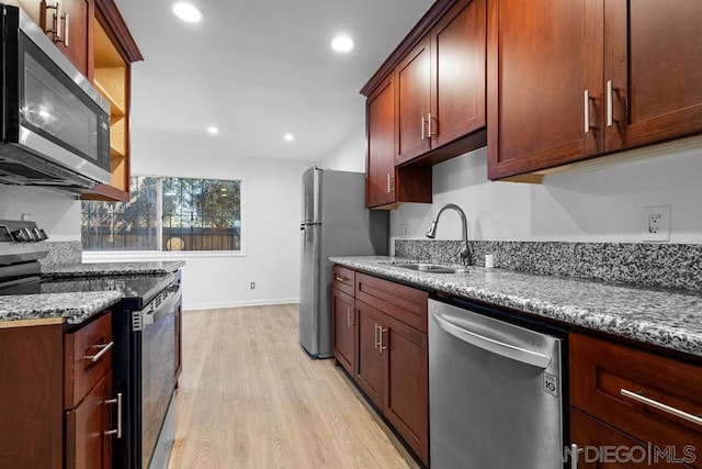 kitchen with sink, light wood-type flooring, stainless steel appliances, and dark stone counters