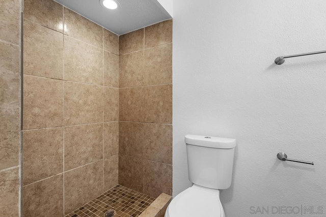 bathroom featuring a tile shower and toilet