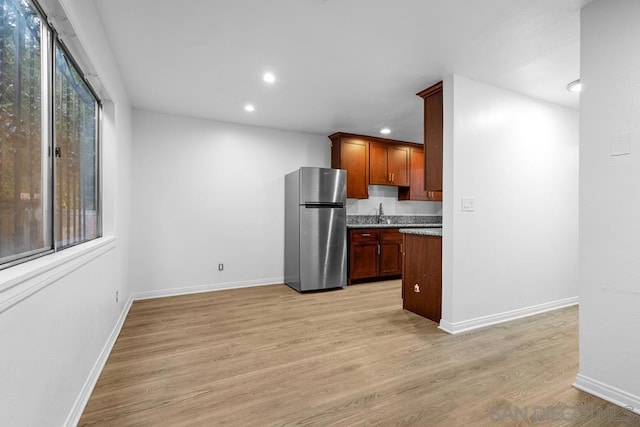 kitchen with stainless steel fridge, light hardwood / wood-style flooring, and sink