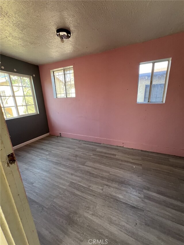 spare room with a textured ceiling and dark hardwood / wood-style floors