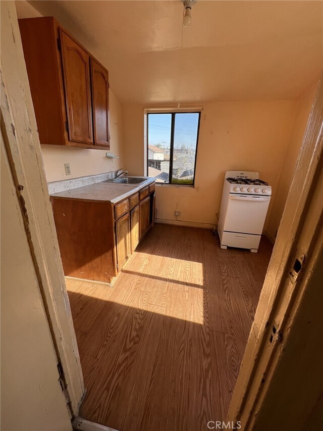 kitchen featuring white gas range, light hardwood / wood-style flooring, and sink