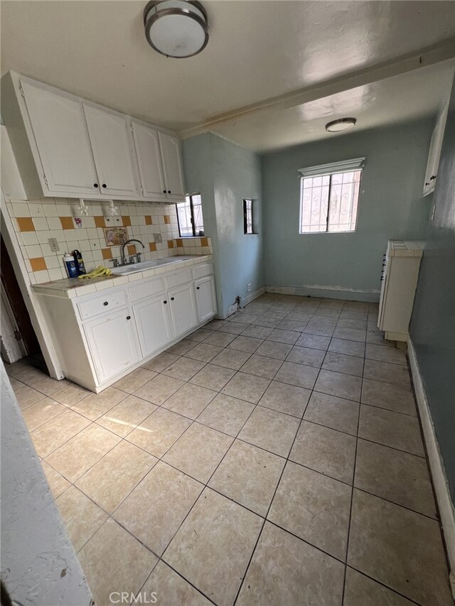 kitchen with sink, light tile patterned flooring, white cabinetry, and tasteful backsplash